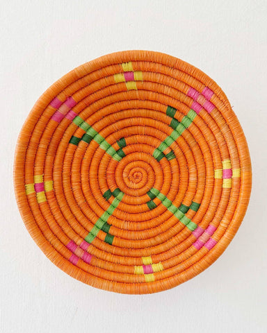 Decorative woven basket with colorful patterns on a white surface