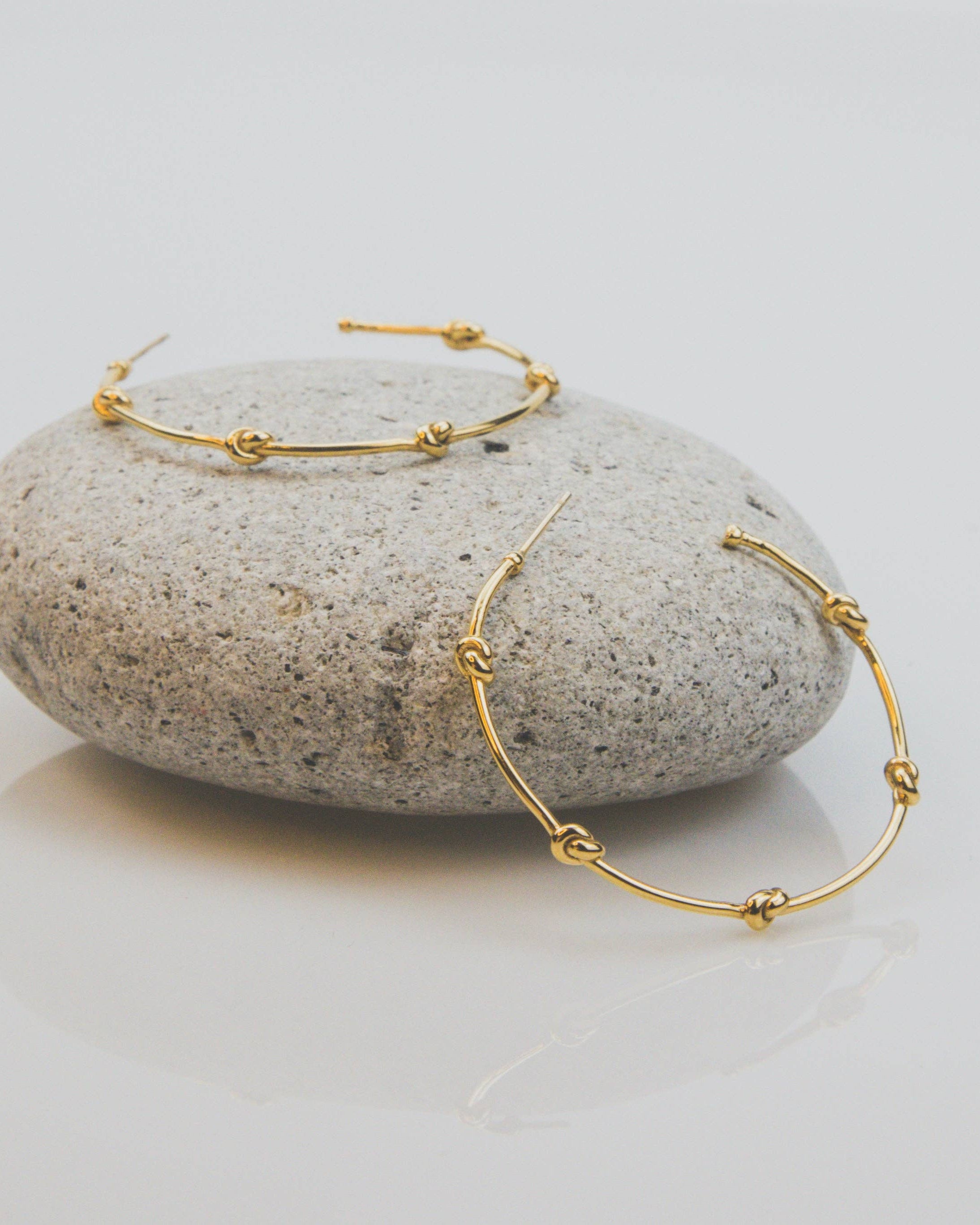 Gold hoop earrings on a stone surface