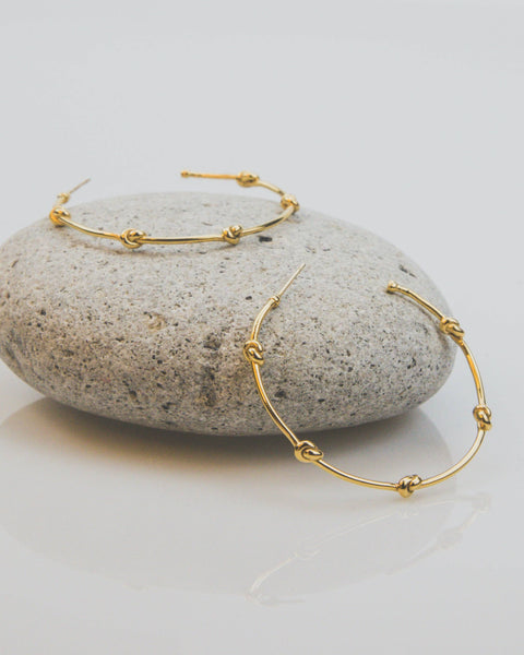 Gold hoop earrings on a stone surface