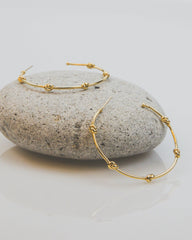 Gold hoop earrings on a stone surface