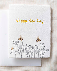 Greeting card with 'Happy Bee Day' text and bee illustrations on a textured fabric background