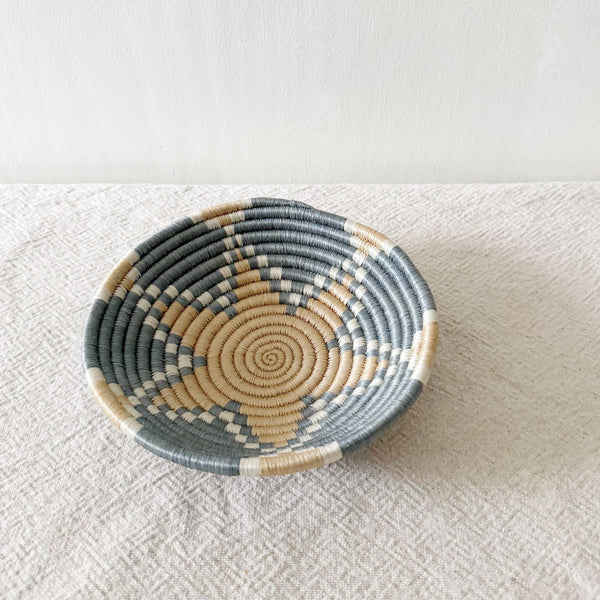Woven basket with concentric circle pattern on a textured surface
