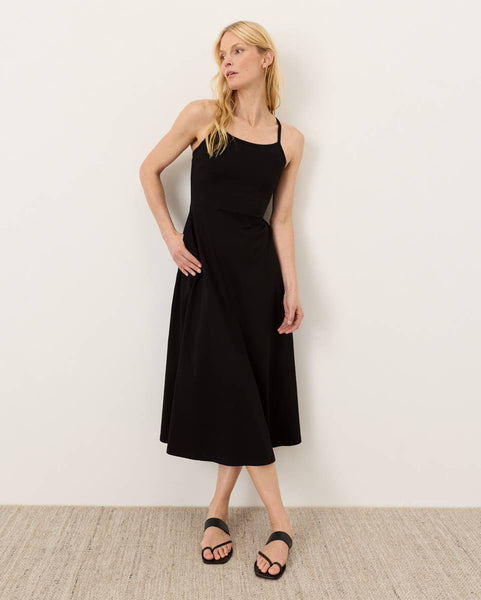 Woman wearing a black dress against a white wall