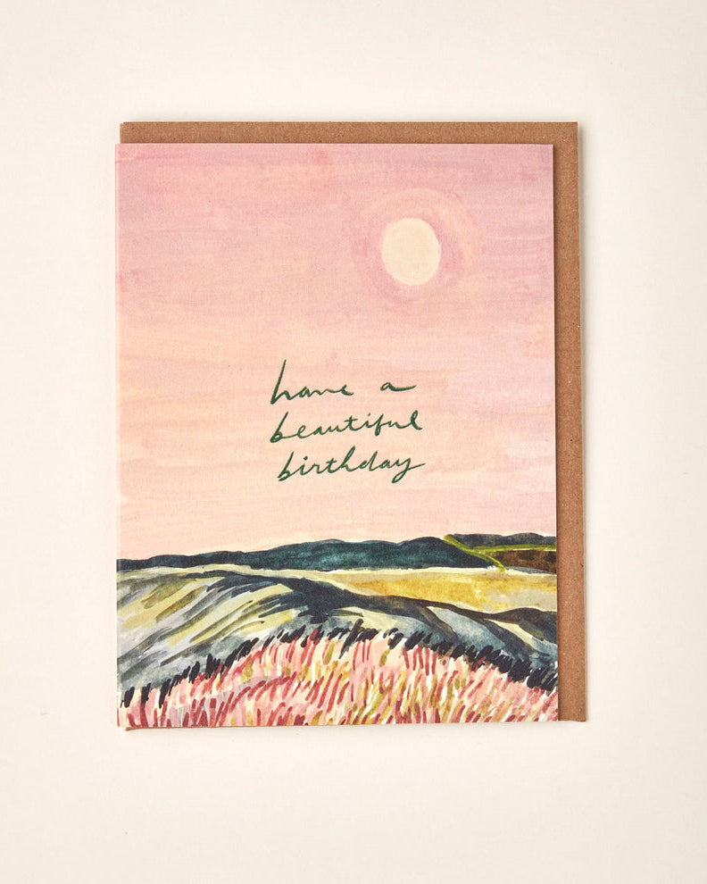 Greeting card with landscape illustration and 'Have a Beautiful Birthday' text on a pink background.