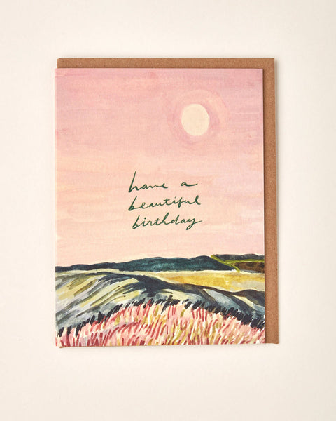 Greeting card with landscape illustration and 'Have a Beautiful Birthday' text on a pink background.