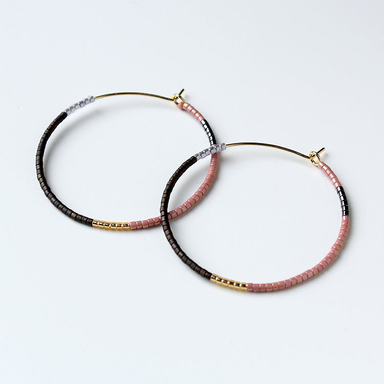 Pair of hoop earrings with black and pink beads on a white background