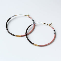 Pair of hoop earrings with black and pink beads on a white background