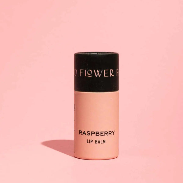 Lip balm with black cap and pink body on a pink background