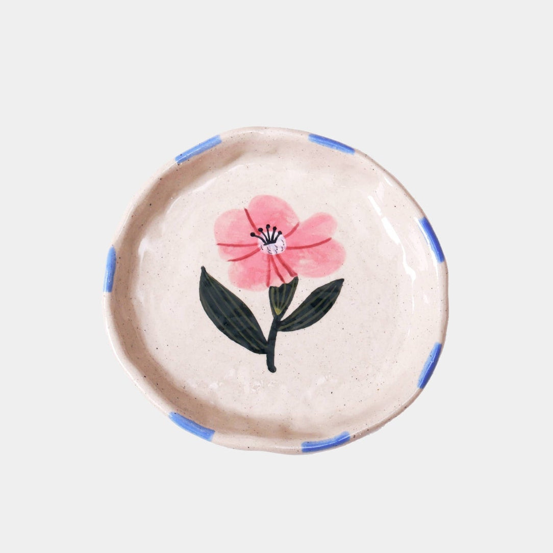 Round decorative item with a pink flower design on a light background