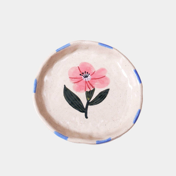 Round decorative item with a pink flower design on a light background