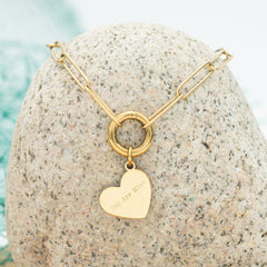 Gold necklace with a heart pendant on a textured stone surface
