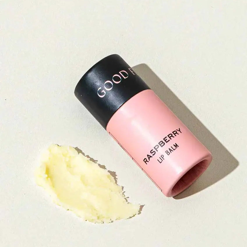 Pink lip balm with black cap on a light beige background