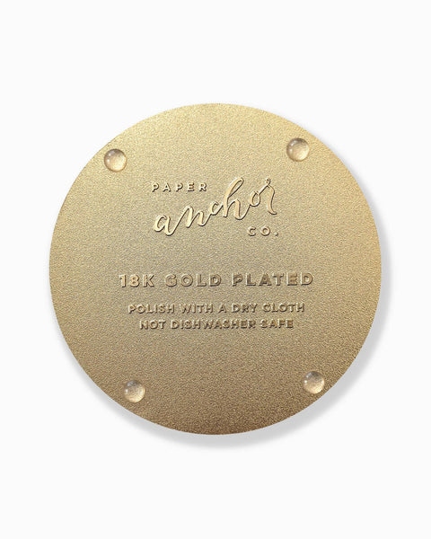 Gold circular coaster with 'Paper Anchor Co.' branding and text on a white background
