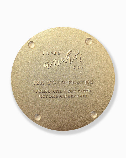 Gold circular coaster back with 'Paper Anchor Co.' branding and text on a white background