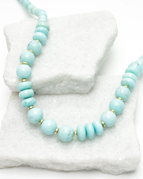 Turquoise beaded necklace on a white stone surface