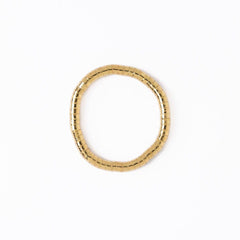 Gold bracelet with a textured design on a white background