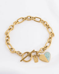 A gold chain bracelet with a toggle clasp, featuring two heart charms: one plain gold and one split with a light mint enamel section.