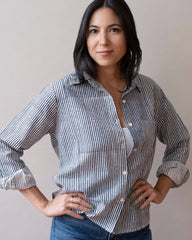 Woman wearing a striped shirt and jeans against a plain background