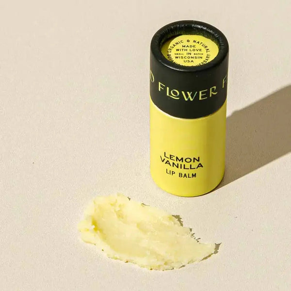 Lemon Vanilla lip balm with a visible brand name on a beige background