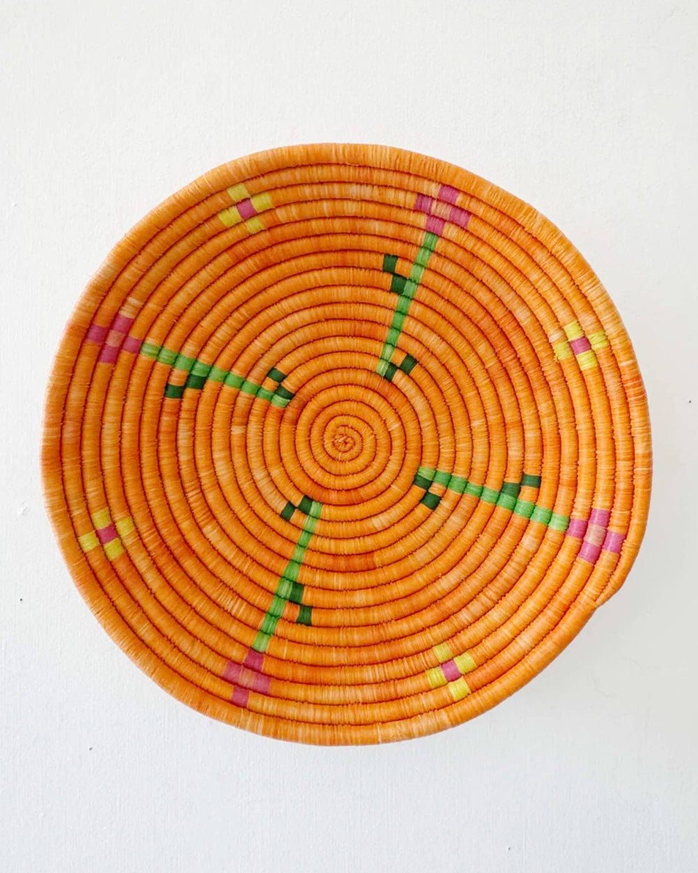Woven basket with orange and green pattern on a white background
