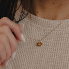 Necklace with a pendant worn by a person, close-up on a neutral background