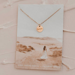 Necklace with 'brave' pendant on a scenic card