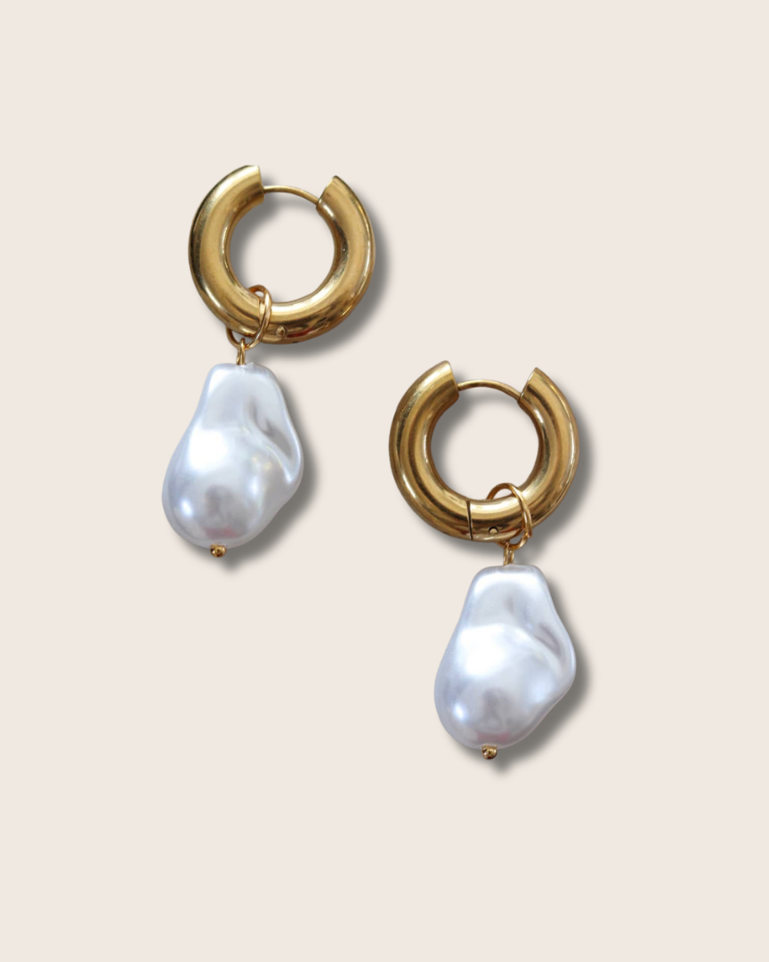 Gold hoop earrings with baroque pearl drops on a beige background