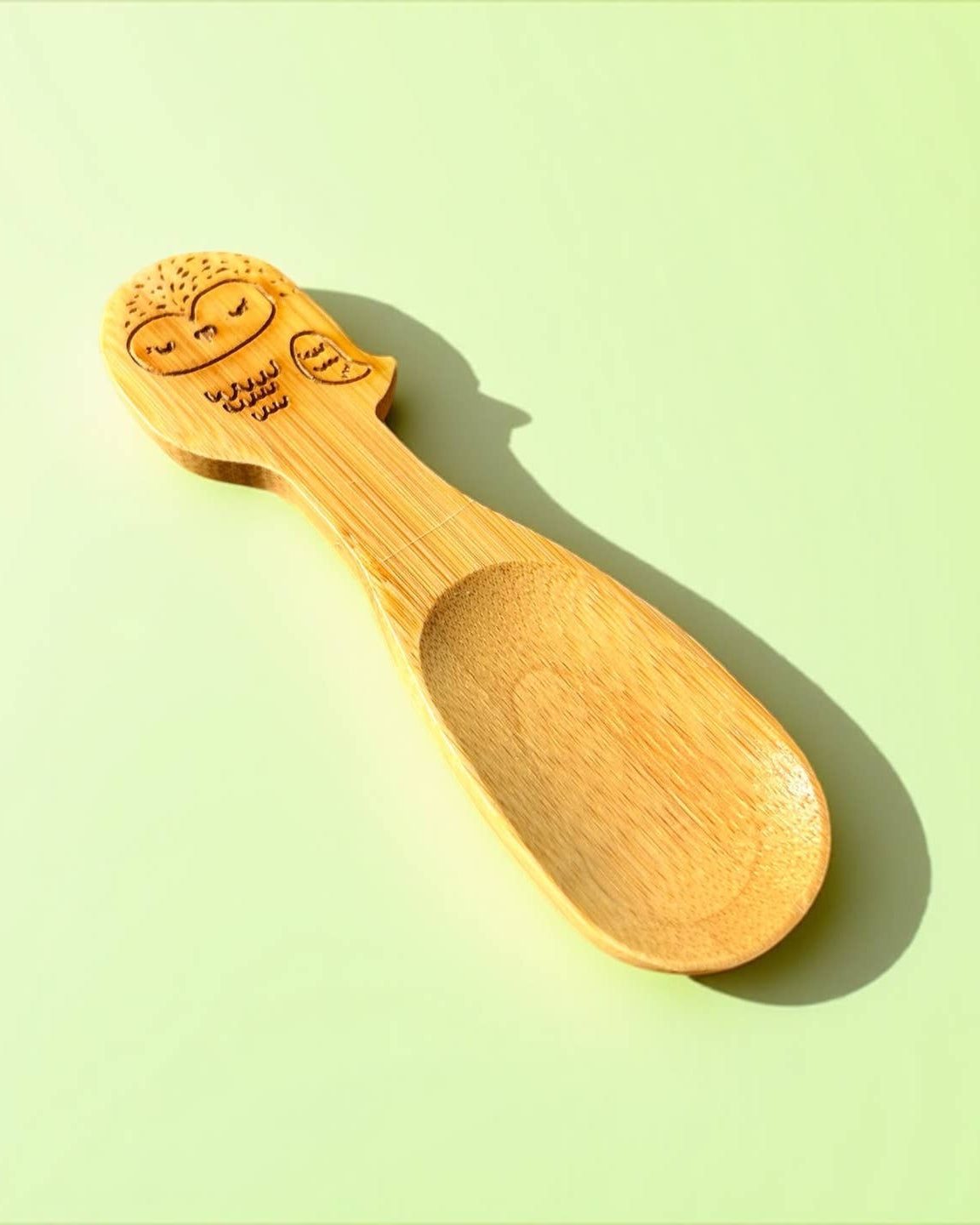 Wooden spoon with face design on a light green background