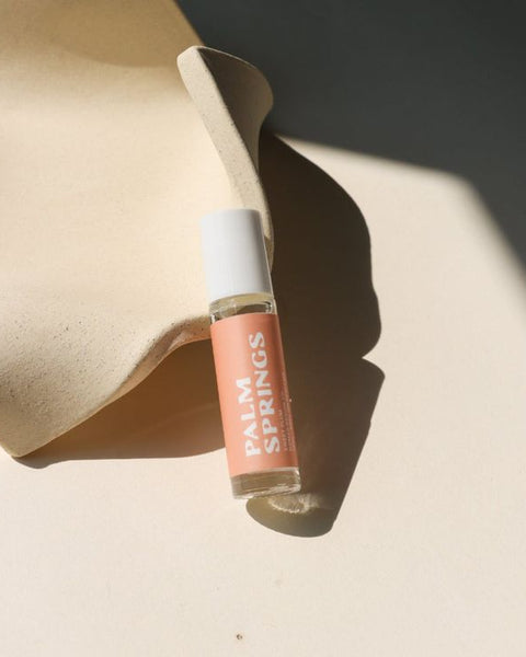 Small glass bottle labeled 'Palm Springs' on a beige surface with soft shadows