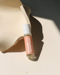Small glass bottle labeled 'Palm Springs' on a beige surface with soft shadows