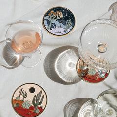 Cactus-themed coasters on a table with glasses of wine.