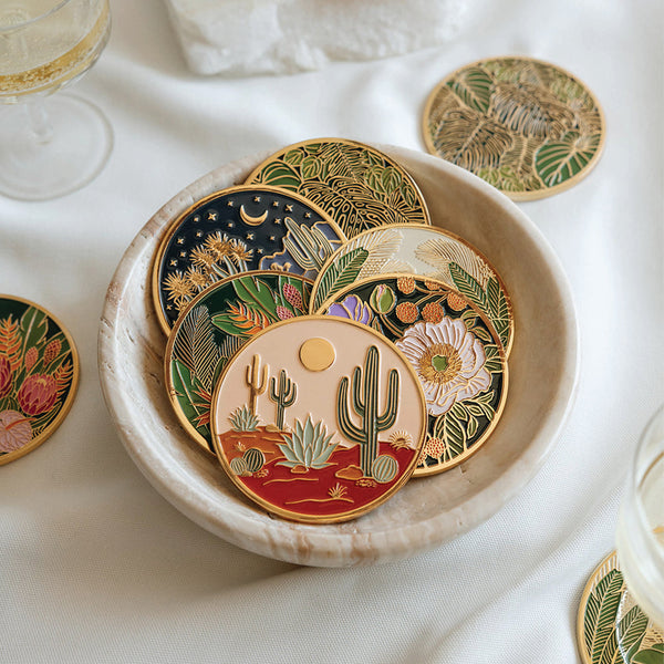 Decorative coasters with desert-themed designs in a bowl on a white surface.