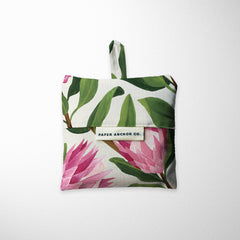 Tote bag with pink flowers and green leaves on a white background, featuring 'Paper Anchor Co.' label.