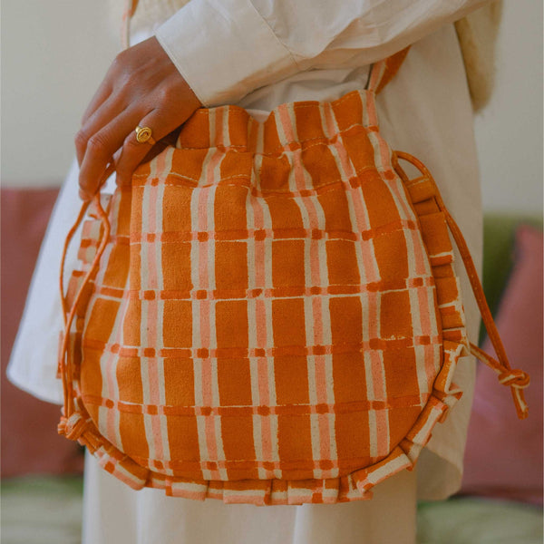 Orange and white checkered bag held by a person with a blurred background