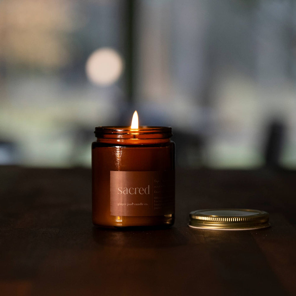 Lit candle in a brown jar on a wooden surface with a blurred background