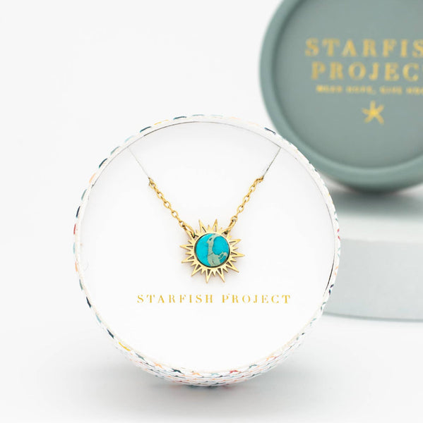 Gold necklace with a turquoise pendant in a Starfish Project box on a white background