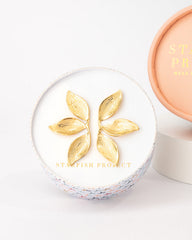 Cosmetic compact with gold leaf design on a white background