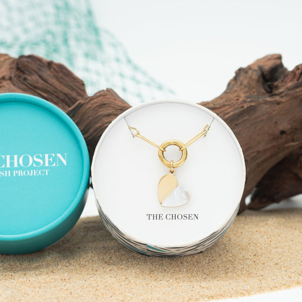 Gold necklace in a 'The Chosen' jewelry box with a turquoise lid on a natural background.