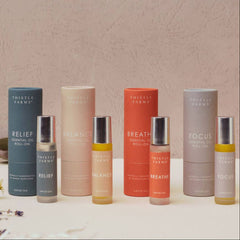 Collection of Thistle Farms essential oil roll-ons on a light background