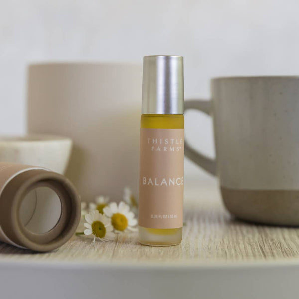 Thistle Farms Balance bottle on a wooden surface with a blurred background