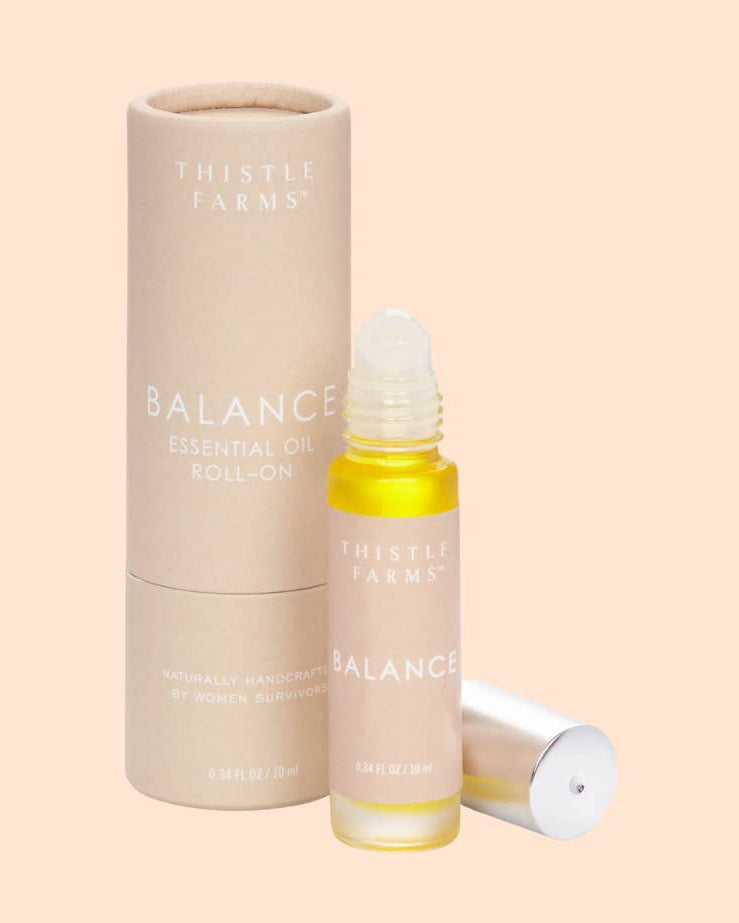 Thistle Farms Balance essential oil roll-on bottle and packaging on a beige background
