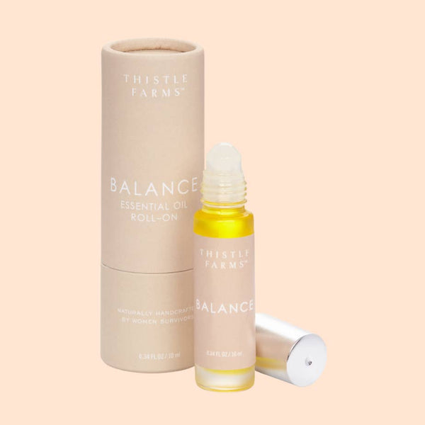 Thistle Farms Balance essential oil roll-on bottle and packaging on a beige background