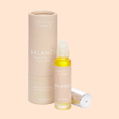 Thistle Farms Balance essential oil roll-on bottle and packaging on a beige background
