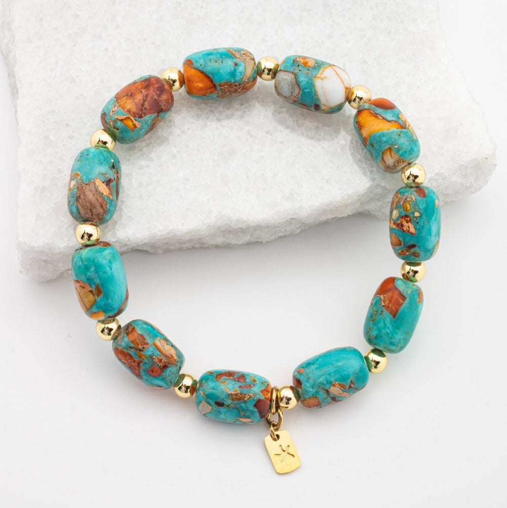 Turquoise and gold beaded bracelet on a white stone background