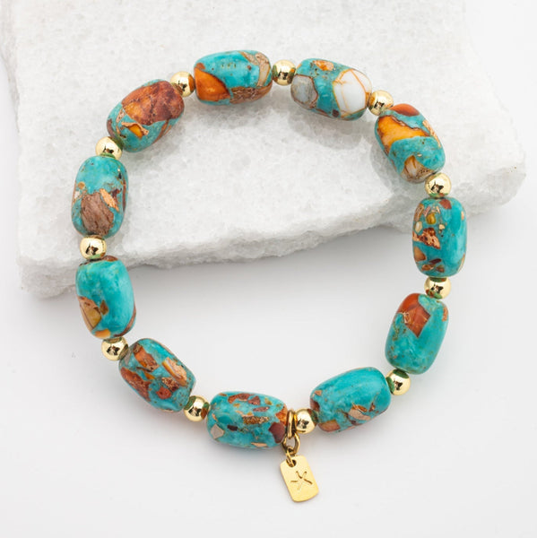 Turquoise and gold beaded bracelet on a white stone background