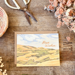 Greeting card with 'Best Wishes' on a wooden surface with decorative elements.