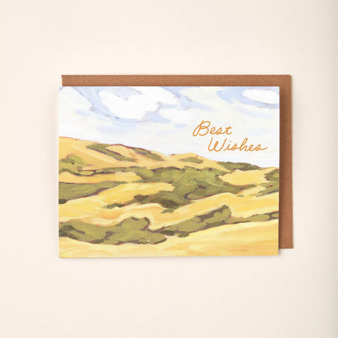 Greeting card with landscape design on a wooden surface with flowers and a pencil.