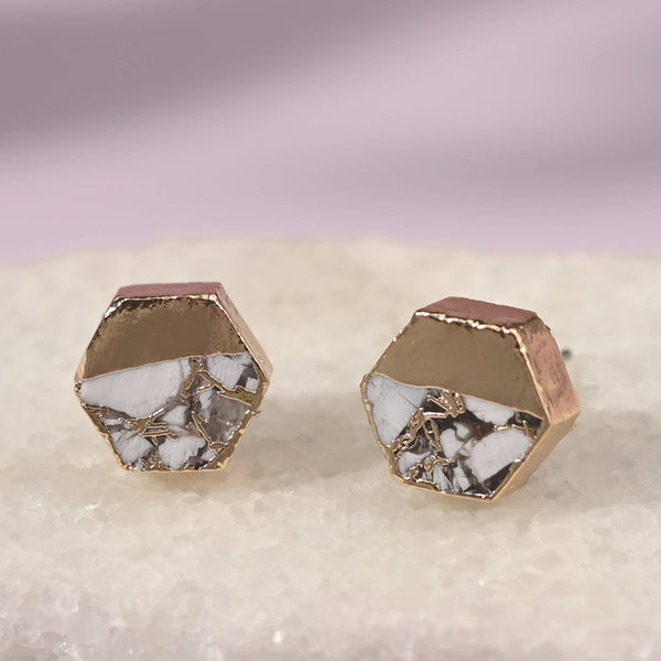 Hexagonal earrings with a rose gold and white stone design on a light gray background